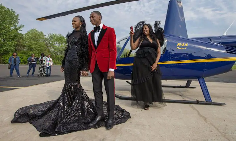 Couple pose for pictures after arriving to prom in a Robinson R44